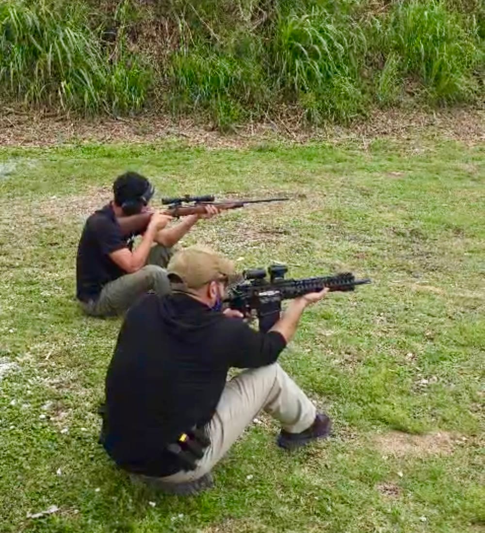 Two Alpha One students shooting rifles from seated positions on the outdoor range